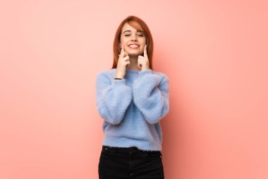 Pembe mutlu ve keyifli bir ifadeyle gülümseyen genç Kızıl saçlı kadın