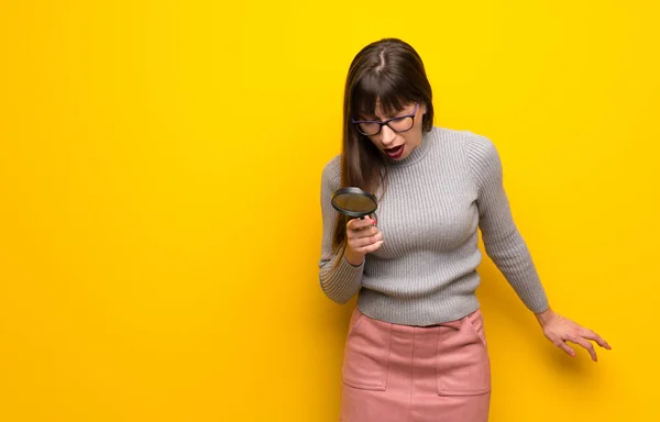 Mulher Com Óculos Sobre Parede Amarela Segurando Uma Lupa — Fotografia de Stock