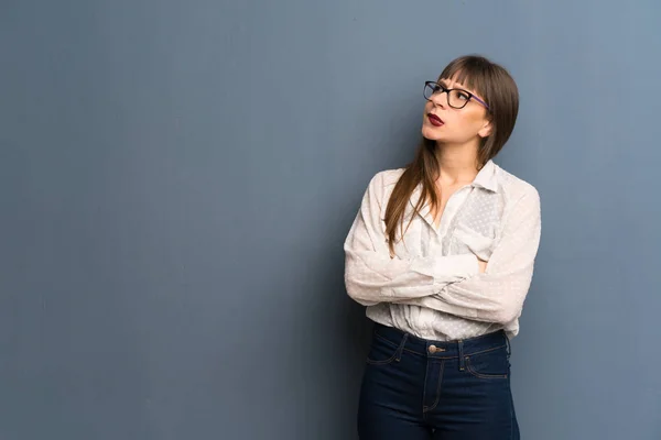 Kobieta Okularach Nad Niebieską Ścianę Wyrazem Twarzy Mylić Podczas Gryzie — Zdjęcie stockowe