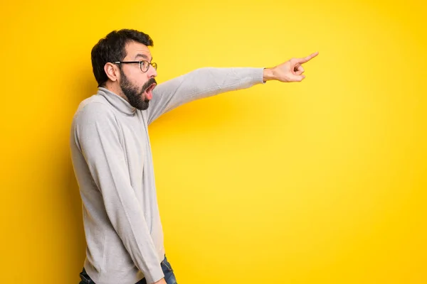 Man with beard and turtleneck pointing away