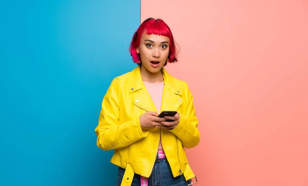 Young woman with yellow jacket surprised and sending a message