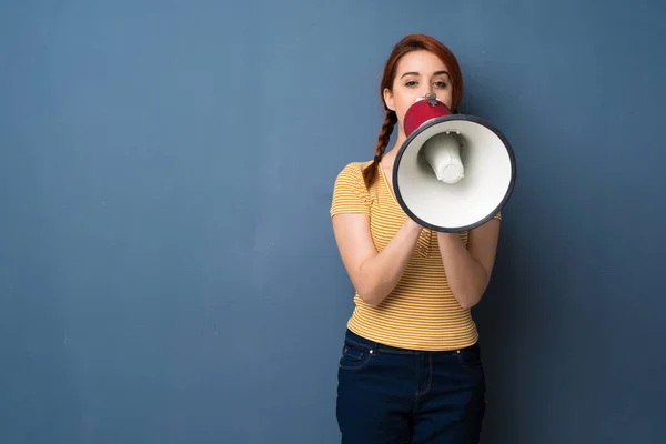 Jonge Roodharige Vrouw Blauwe Achtergrond Schreeuwen Door Een Megafoon — Stockfoto