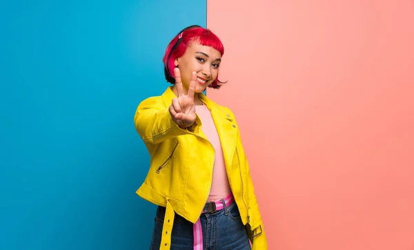 Young woman with yellow jacket smiling and showing victory sign