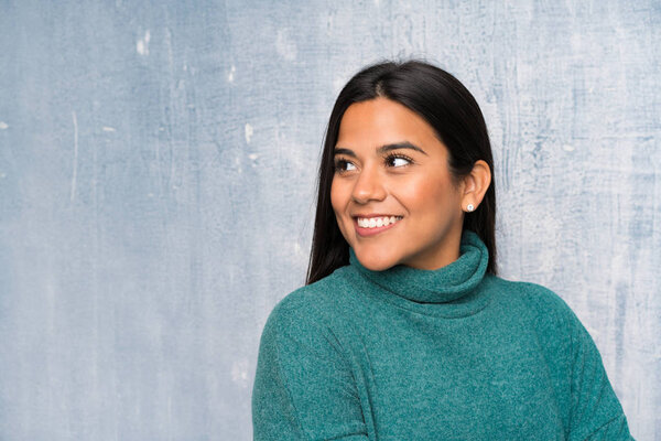 Молодая колумбийская девушка смеется над гранж-стеной
