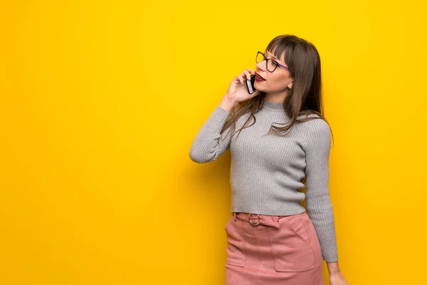 Женщина Очках Желтой Стене Поддерживает Разговор Мобильным Телефоном — стоковое фото