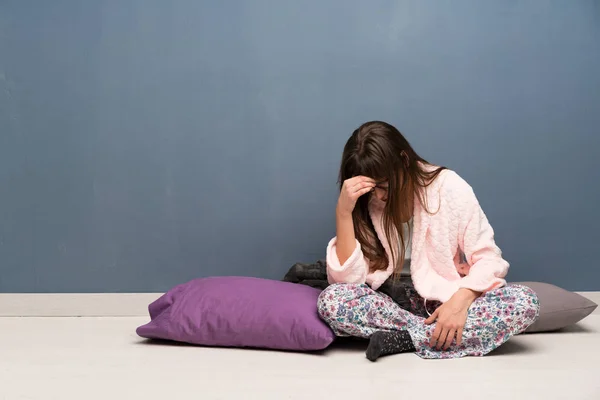 Woman in pajamas on the floor with tired and sick expression