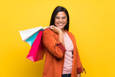 Bir sürü alışveriş torbaları tutan sarı duvarın üzerinden Kolombiyalı genç kız