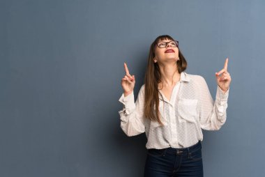 Mavi duvar üzerinde gözlük ile kadın indeks parmak büyük bir fikir ile işaret