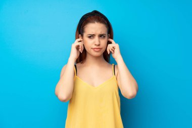 Mavi arka plan sinirli ve kaplama kulaklarını elleriyle genç Kızıl saçlı kadın