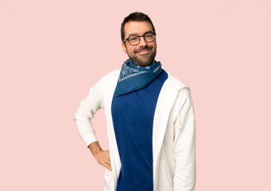 Gözlük ile yakışıklı adam kalça ve izole pembe arka planda gülümseyen kollar ile poz