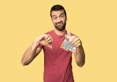 Adam çok para alarak iyi kötü bir işaret yapıyor. İzole sarı arka planda Evet veya değil arasında kararsız