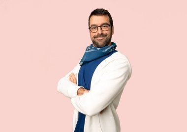 Gözlük ile yakışıklı adam izole pembe arka plan üzerinde gülümseyen ederken silah lateral pozisyonda geçti tutmak