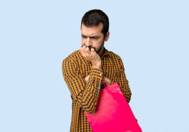 İzole mavi arka plan üzerinde şüphe sahip alışveriş torbaları ile adam