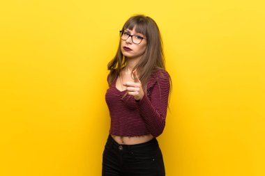 Cepheye dönük ve hayal kırıklığına uğramış sarı duvarın üzerinden gözlüklü kadın