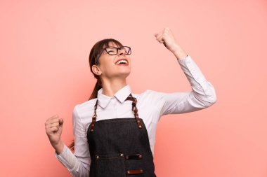 Genç garson bir zaferi kutlayan pembe bir arka plan üzerinde