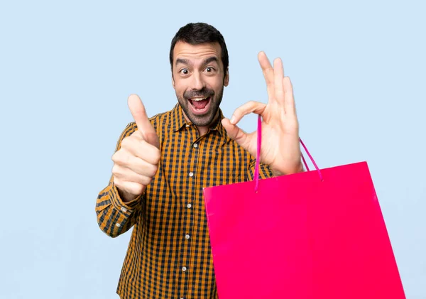 Man Shopping Bags Showing Sign Giving Thumb Gesture Isolated Blue — Stock Photo, Image