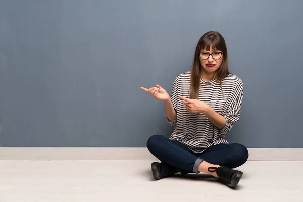 Woman Glasses Sitting Floor Frightened Pointing Side — Zdjęcie stockowe