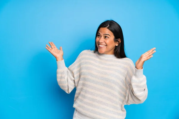 驚きの顔の表情でセーターを持つ若いコロンビアの女の子 — ストック写真
