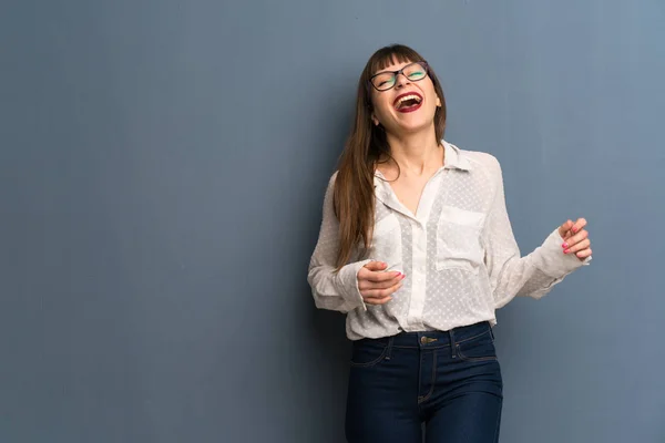 Kobieta Okularach Nad Niebieską Ścianę Uśmiechając Się Dużo Podczas Wkładania — Zdjęcie stockowe