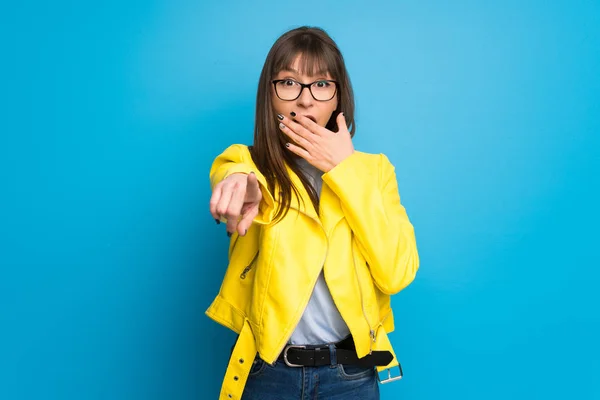 Jonge Vrouw Met Gele Jas Blauwe Achtergrond Aan Wijzen Met — Stockfoto