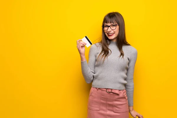 Γυναίκα Γυαλιά Πάνω Από Κίτρινο Τοίχο Κρατώντας Μια Πιστωτική Κάρτα — Φωτογραφία Αρχείου