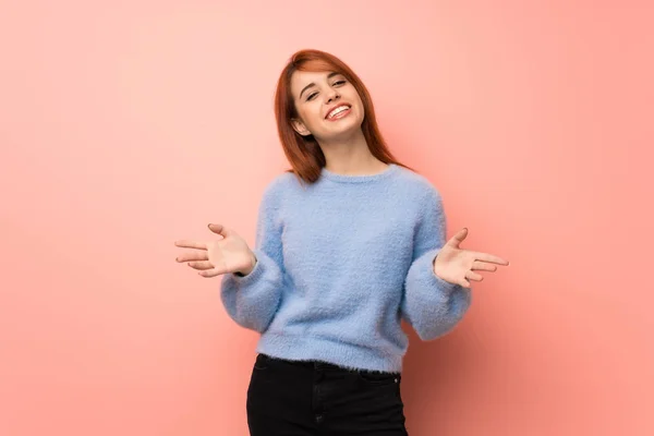 Young redhead woman over pink background smiling