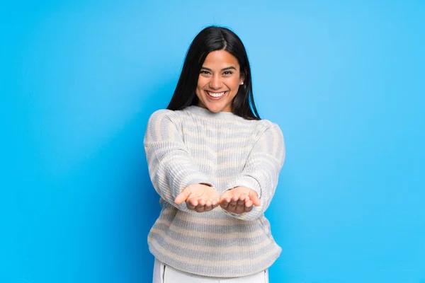 Jovem Colombiana Com Suéter Segurando Copyspace Imaginário Palma Mão Para — Fotografia de Stock