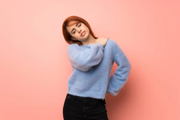 Young redhead woman over pink background suffering from pain in shoulder for having made an effort