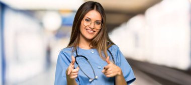 Öne doğru işaret ve bir hastanede gülümseyen genç hemşire