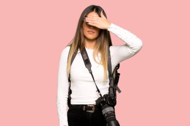 Genç fotoğrafçı kadın gözleri eller tarafından kapsayan. Bir şey izole pembe arka plan görmek istiyor musunuz