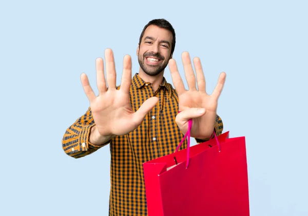 Man Med Shopping Väskor Räkna Nio Med Fingrarna Isolerad Blå — Stockfoto