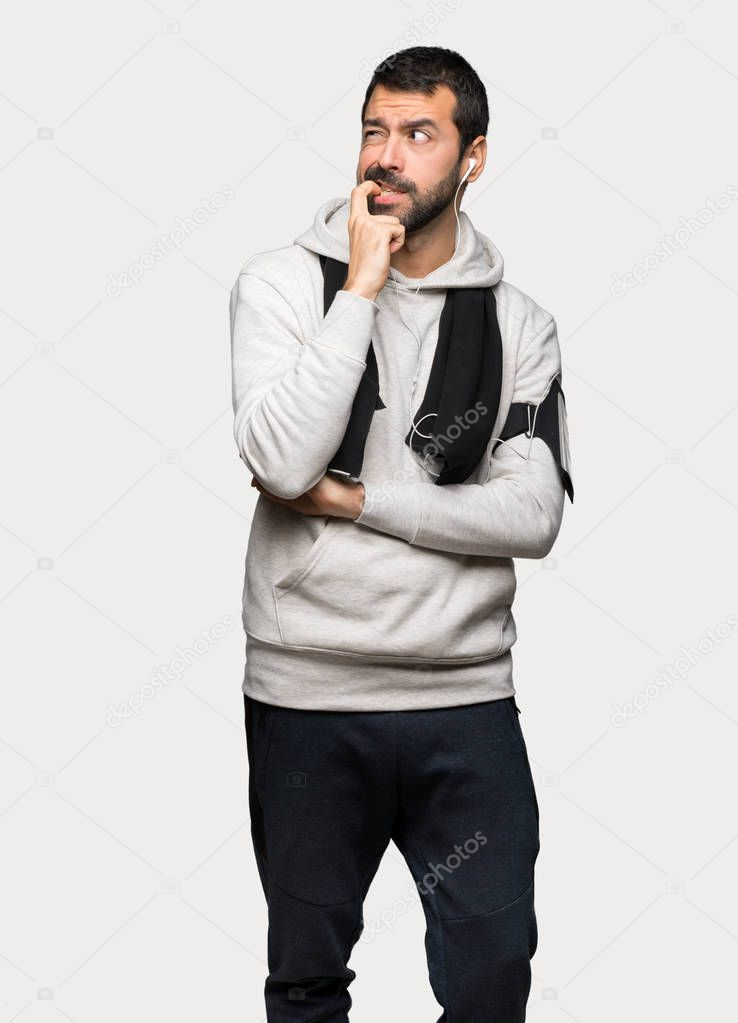 Sport man having doubts while looking up over isolated grey background