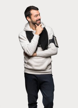 İzole gri arka plan üzerinde çene el ile yan seyir spor adam