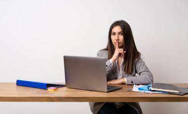 Bir ofiste iş kadını ağzını parmak koyarak sessizlik jest bir işareti gösteren