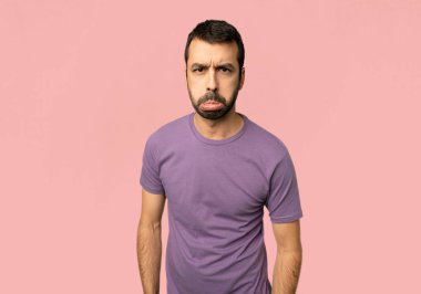 İzole pembe arka planda üzücü ve depresif ifade ile yakışıklı adam