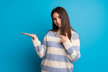 Genç kadın boşaltmak hayali avuç içinde tutan mavi duvarın üzerinden bir reklam eklemek için