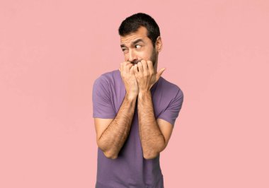 Yakışıklı adam biraz gergin ve izole pembe arka planda ağız eller koyarak korkuyor