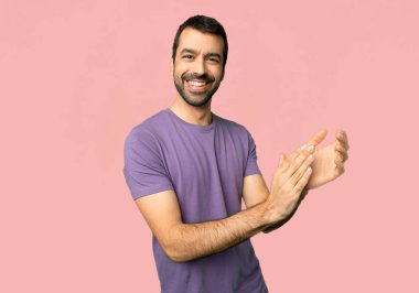 Yakışıklı adam izole pembe bir arka plan üzerinde bir konferansta sunum sonrası alkış