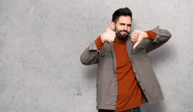 İyi-kötü işaret yapma sakallı yakışıklı adam. Kararsız Evet arasında veya dokulu duvar üzerinde değilken