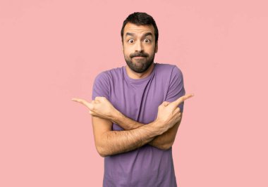 Yakışıklı adam lateraller izole pembe arka plan üzerinde şüphe sahip işaret