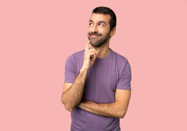 İzole pembe arka plan üzerinde bakarak bir fikir düşünme yakışıklı adam