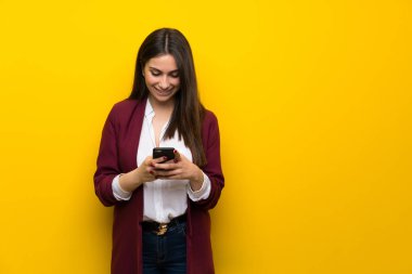 Genç kadın sarı duvar mobil ileti gönderme