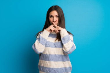 Sessiz jest bir işareti gösteren mavi duvar üzerinde genç kadın