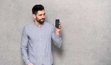 Kırık smartphone dokulu duvar'ın üstüne holding ile gömlek ile zarif adam sorunlu