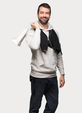 Bir sürü alışveriş torbaları izole gri arka plan üzerinde tutan spor adamı