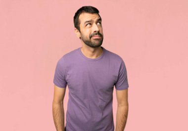 Yakışıklı adam izole pembe arka planda ciddi yüz ile bakıyor