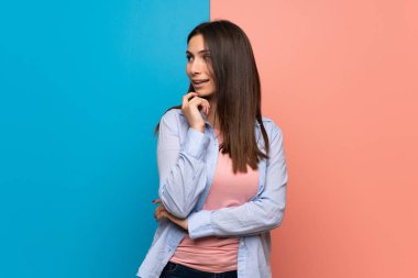 Pembe ve mavi duvara bakarak bir fikir düşünme genç kadın