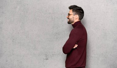 Dokulu duvarın üzerinden lateral pozisyonda gözlüklü yakışıklı adam