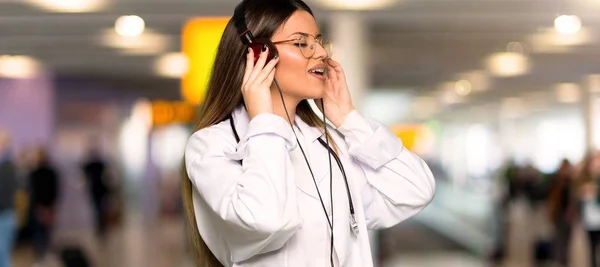 Young doctor woman listening to music with headphones in a hospital