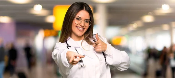 年轻的医生妇女指着前面 微笑着在医院 — 图库照片